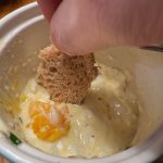 Dipping bread into eggs baked in anchovy cream sauce.